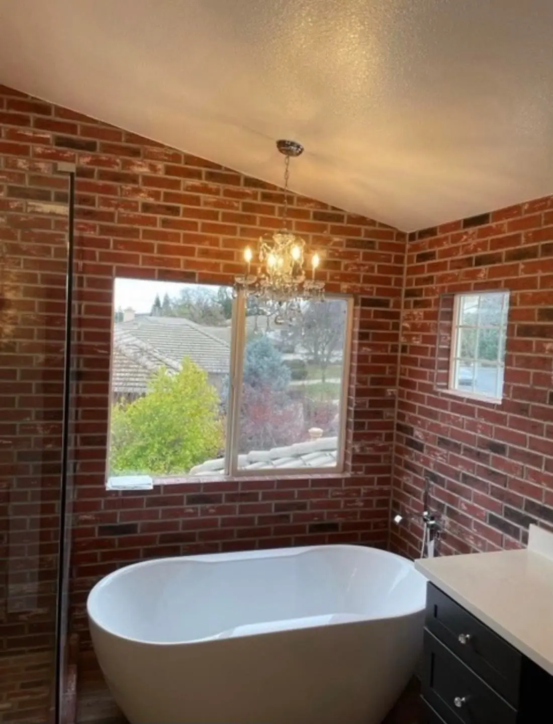 Bathroom with exposed brick accent wall and freestanding tub