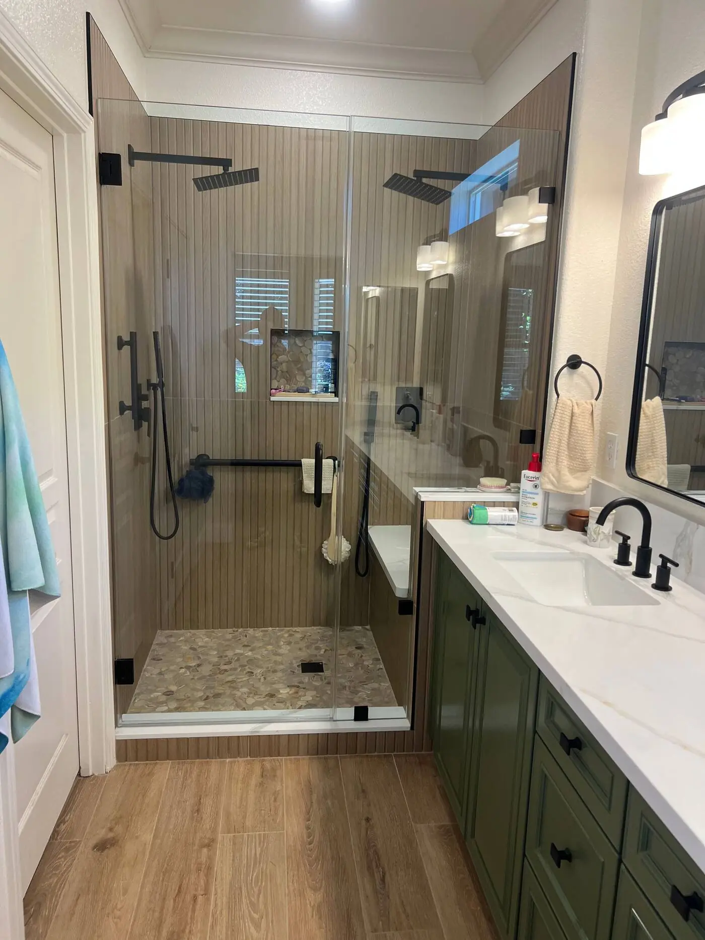 Remodeled master bathroom with green vanity and glass shower by Valley Home Construction