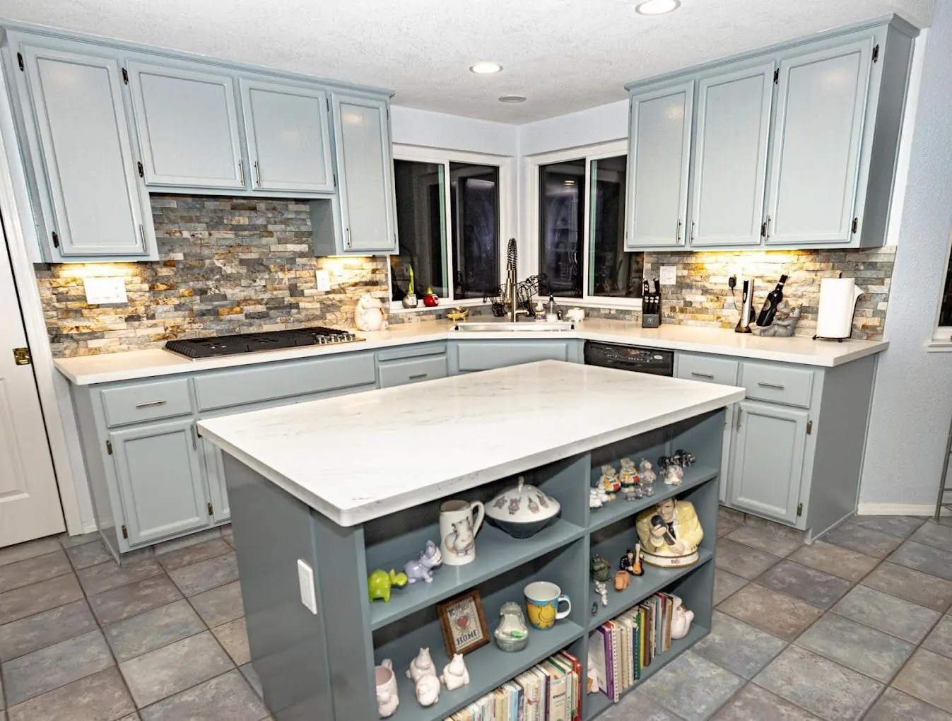 Sage green kitchen island with stone backsplash