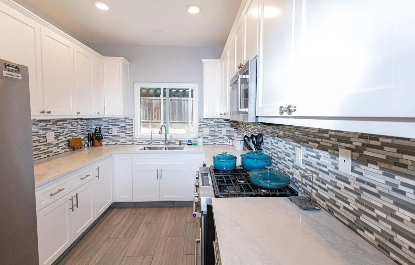 White kitchen with mosaic tile backsplash and light wood floors