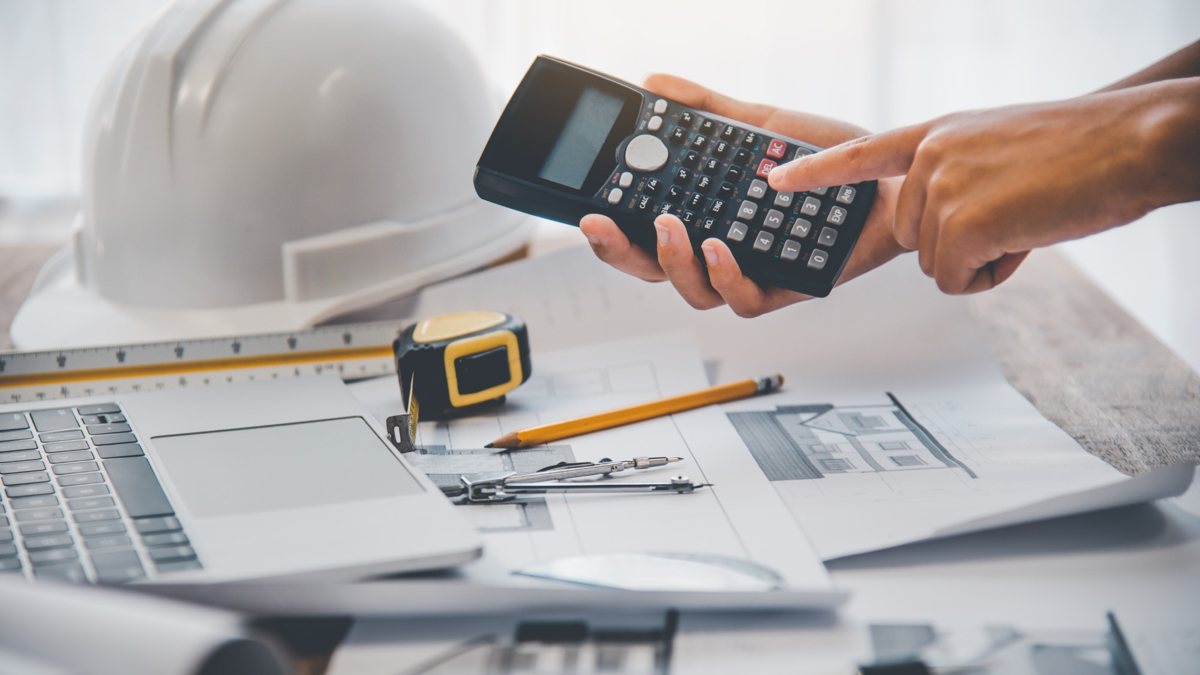 Working out a project price with a calculator over the plans